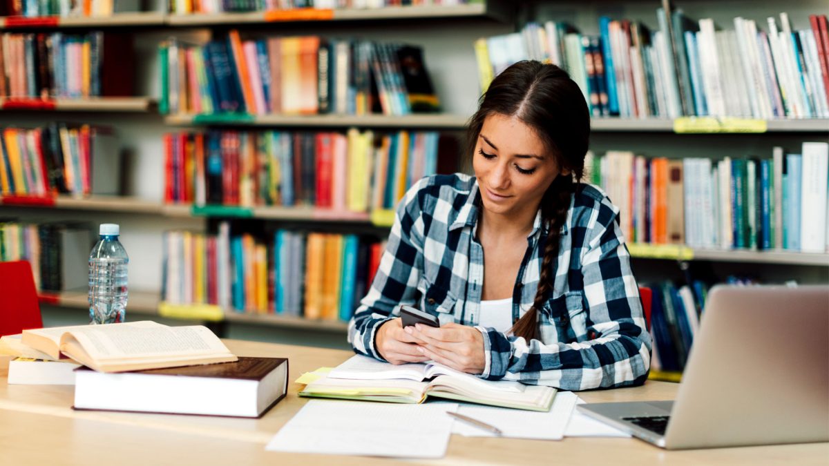 estudiante-universitaria-con-smartphone-en-biblioteca.jpg