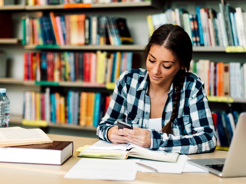 estudiante-universitaria-con-smartphone-en-biblioteca.jpg