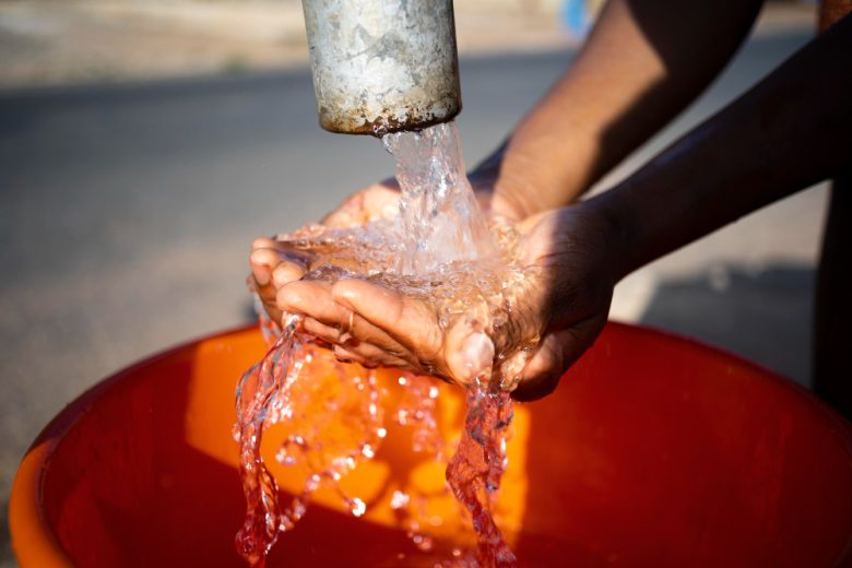 mujer-africana-vertiendo-agua-recipiente-al-aire-libre.jpg