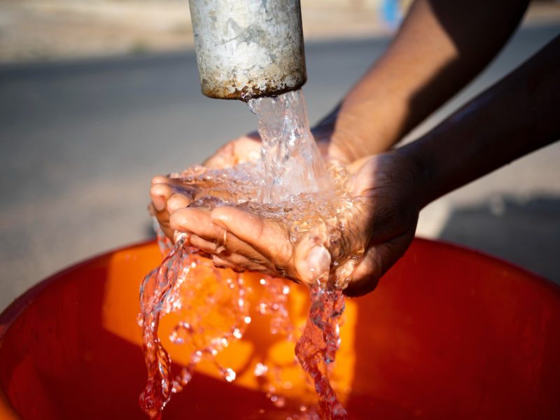 mujer-africana-vertiendo-agua-recipiente-al-aire-libre.jpg