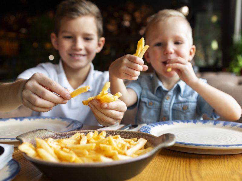 medium-shot-smiley-boys-eating-fries.jpg
